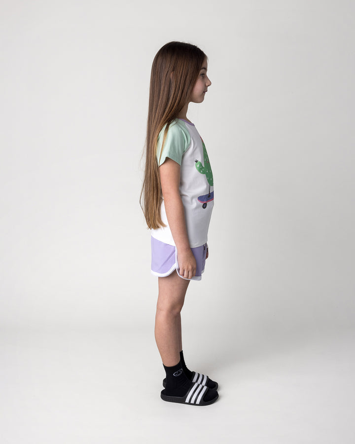Kid wearing the Skate Cactus Tee in white and mint with the Sprint Short in lilac and white, side view