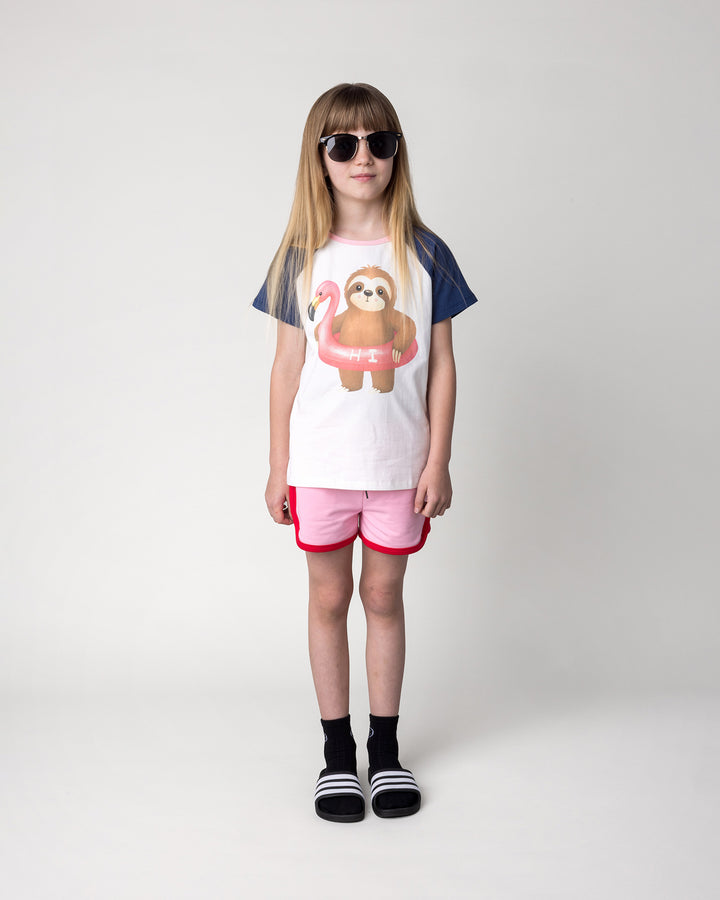 Kid wearing the Swimming Sloth Tee in white, ink and pink with the Sprint Short in pink and red, front view