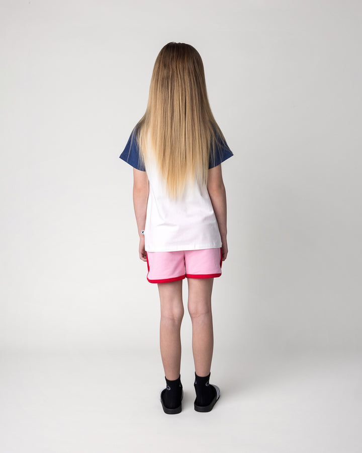 Kid wearing the Swimming Sloth Tee in white, ink and pink with the Sprint Short in pink and red, back view