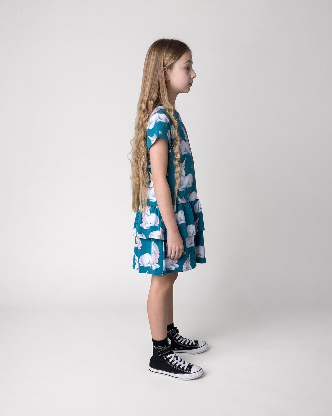 Kid wearing the Daydreaming Unicorn Dress in teal, side view