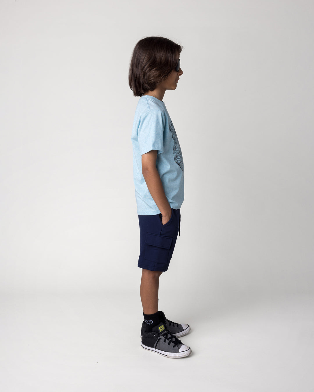 Kid wearing the Boarding Bear Tee in blue marle with the Deluxe Cargo Short in ink, side view