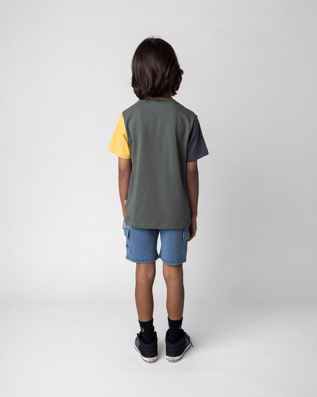 Kid wearing the Boarding Bear Tee in forest, dark grey and yellow with the Blasted Deluxe Cargo Short in midnight wash, back view
