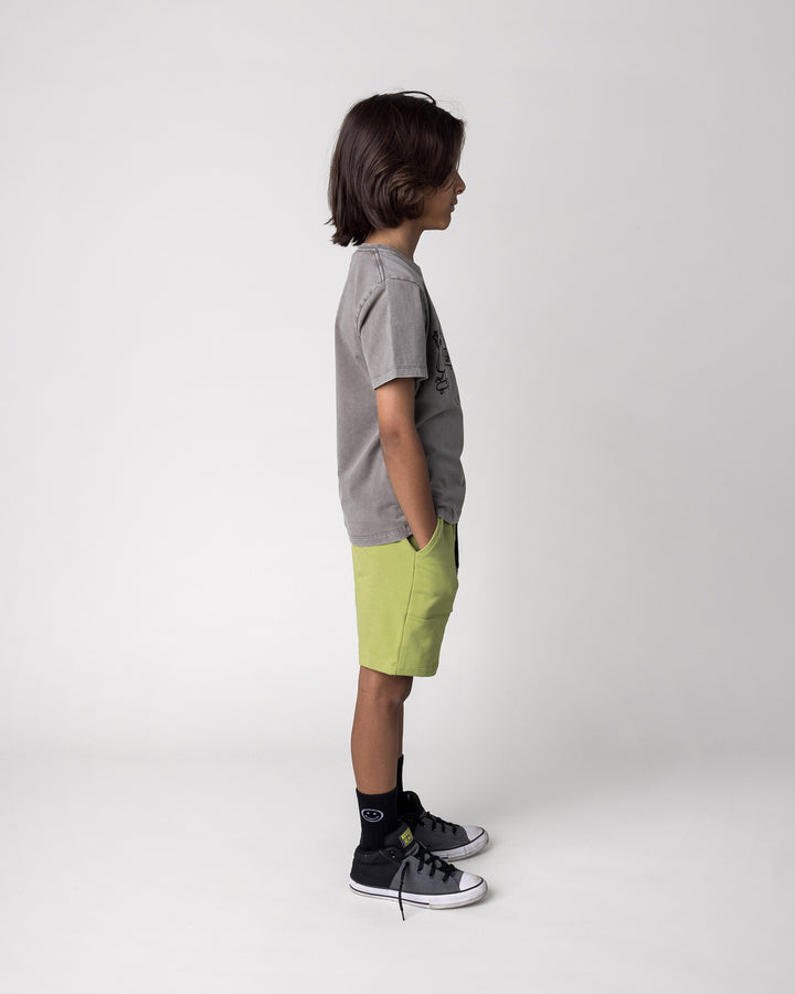 Kid wearing the Cool Crew Tee in grey wash with the Track Short in lime, side view