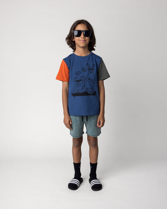 Kid wearing the Chill Mates Tee in midnight, orange and forest with the Blasted Track Short in forest wash, front view