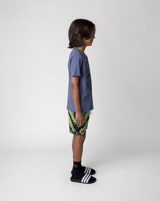 Kid wearing the Chill Sloth Tee in muted blue with the Strike Short in lime, side view