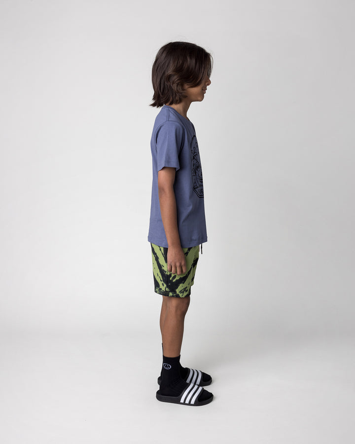 Kid wearing the Chill Sloth Tee in muted blue with the Strike Short in lime, side view