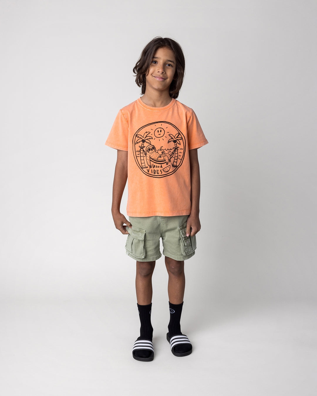 Kid wearing the Chill Sloth Tee in orange wash, front view
