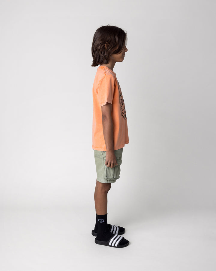 Kid wearing the Chill Sloth Tee in orange wash, side view