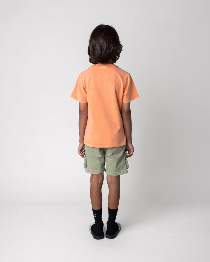Kid wearing the Chill Sloth Tee in orange wash, back view