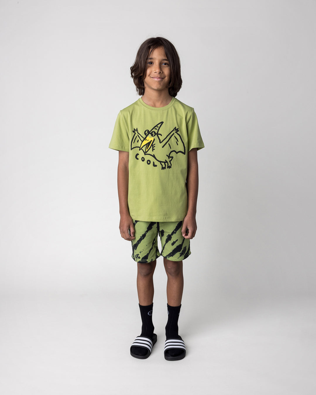 Kid wearing the Cool Pterodactyl Tee in lime with the Strike Short in lime, front view