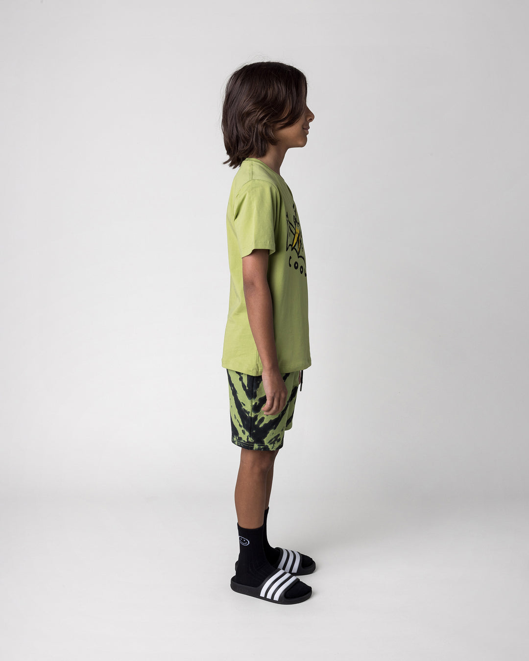 Kid wearing the Cool Pterodactyl Tee in lime with the Strike Short in lime, side view