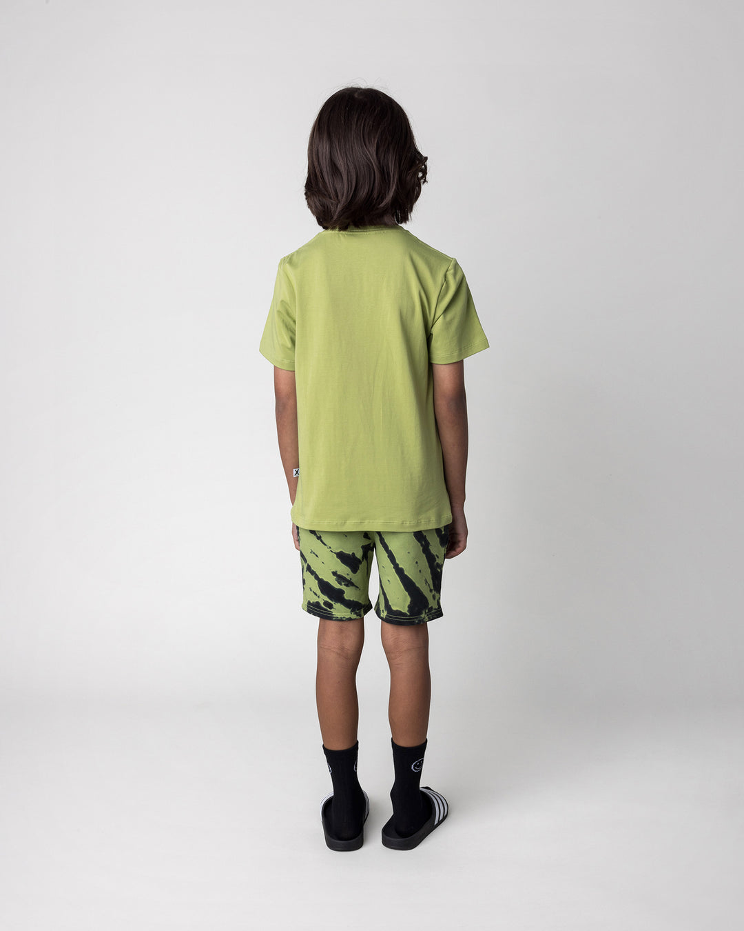 Kid wearing the Cool Pterodactyl Tee in lime with the Strike Short in lime, back view