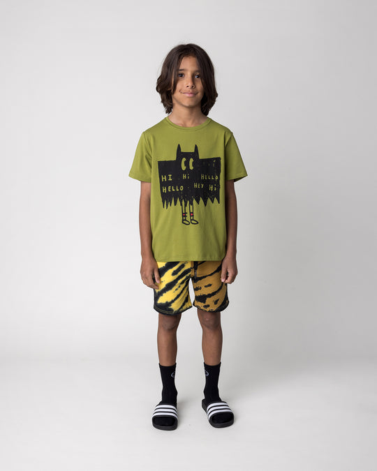 Kid wearing the Greetings Bat Tee in olive with the Duo Tie Dye Short in lemon and rust, front view