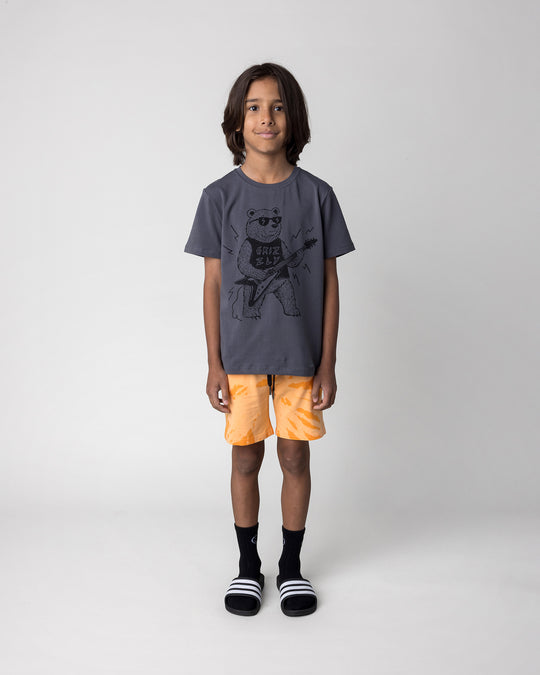 Kid wearing the Grizzly Tee in dark grey with the Splatter Short in orange, front view