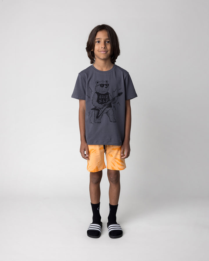 Kid wearing the Grizzly Tee in dark grey with the Splatter Short in orange, front view