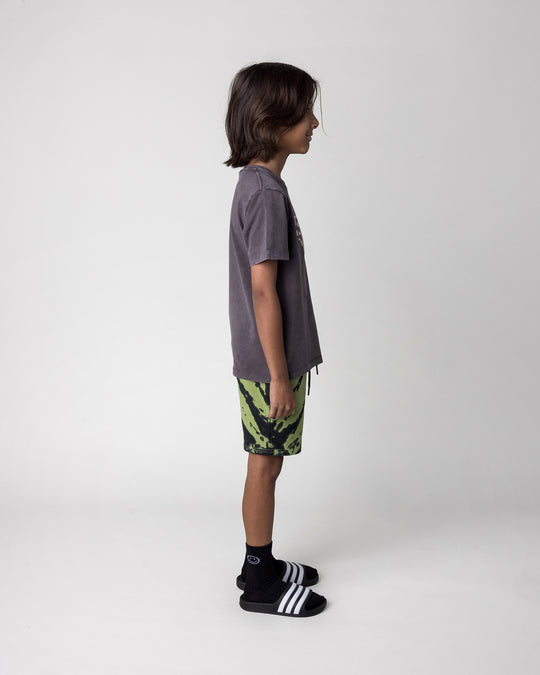 Kid wearing the Hello Bat Tee in black wash with the Strike Short in lime, side view