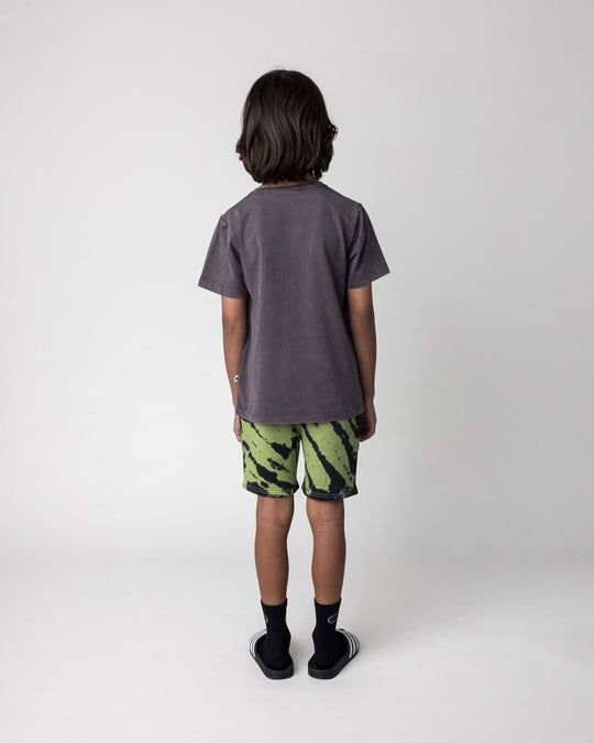 Kid wearing the Hello Bat Tee in black wash with the Strike Short in lime, back view