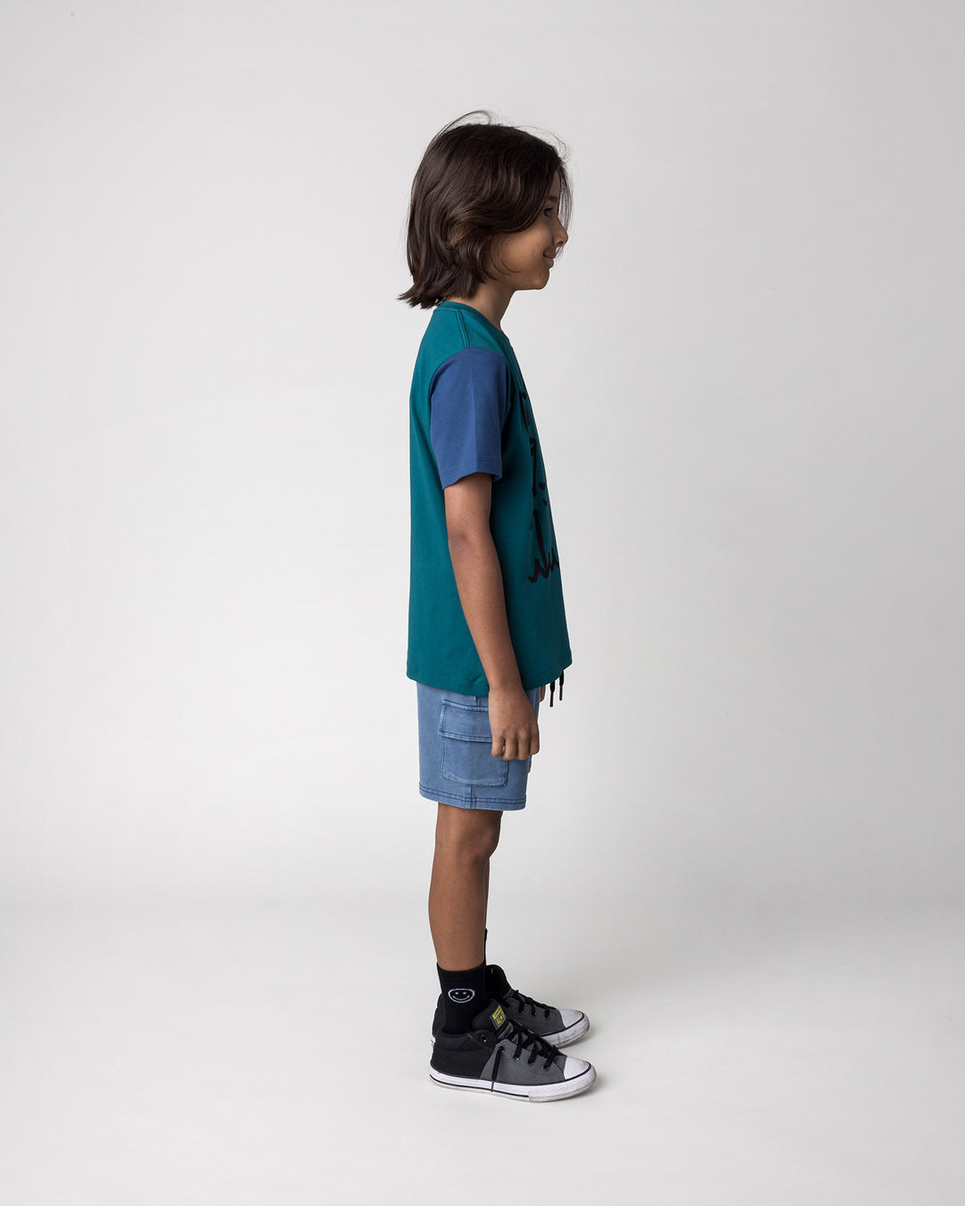 Kid wearing the Hi Hammerhead Tee in dark teal and midnight with the Blasted Deluxe Cargo Short in midnight wash, side view
