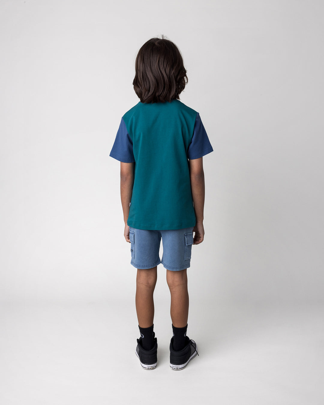 Kid wearing the Hi Hammerhead Tee in dark teal and midnight with the Blasted Deluxe Cargo Short in midnight wash, back view