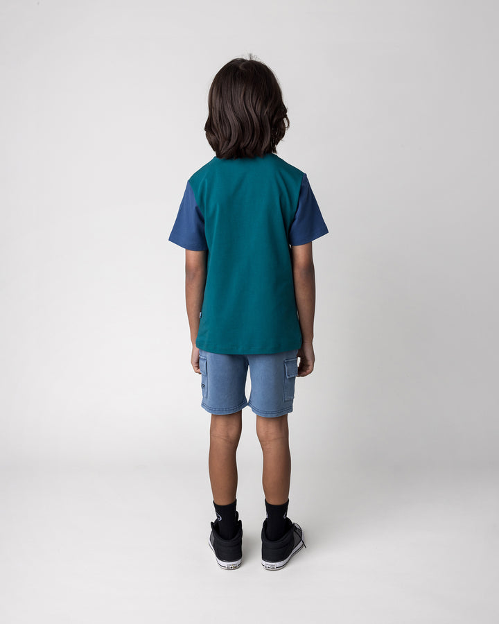 Kid wearing the Hi Hammerhead Tee in dark teal and midnight with the Blasted Deluxe Cargo Short in midnight wash, back view