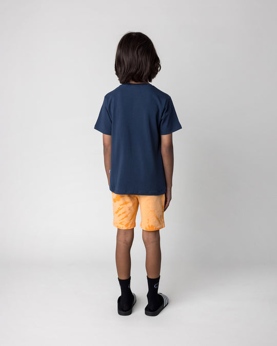 Kid wearing the Howdy Lizard Tee in ink with the Splatter Short in orange, back view