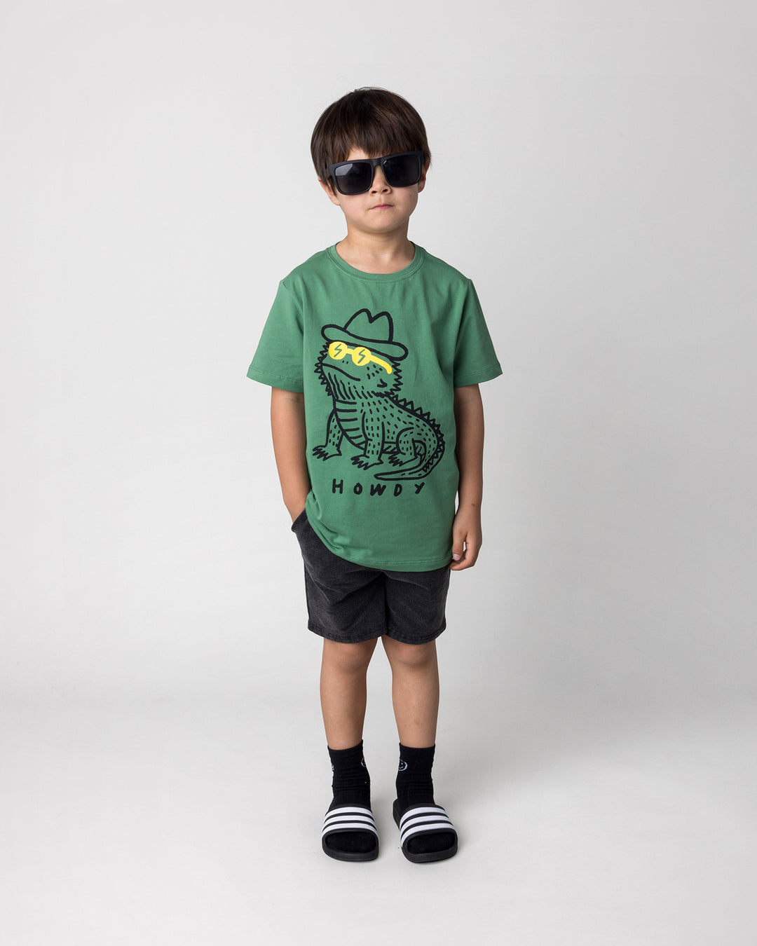 Kid wearing the Howdy Lizard Tee in turf with the Blasted Panel Short in black wash, front view