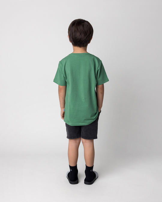 Kid wearing the Howdy Lizard Tee in turf with the Blasted Panel Short in black wash, back view