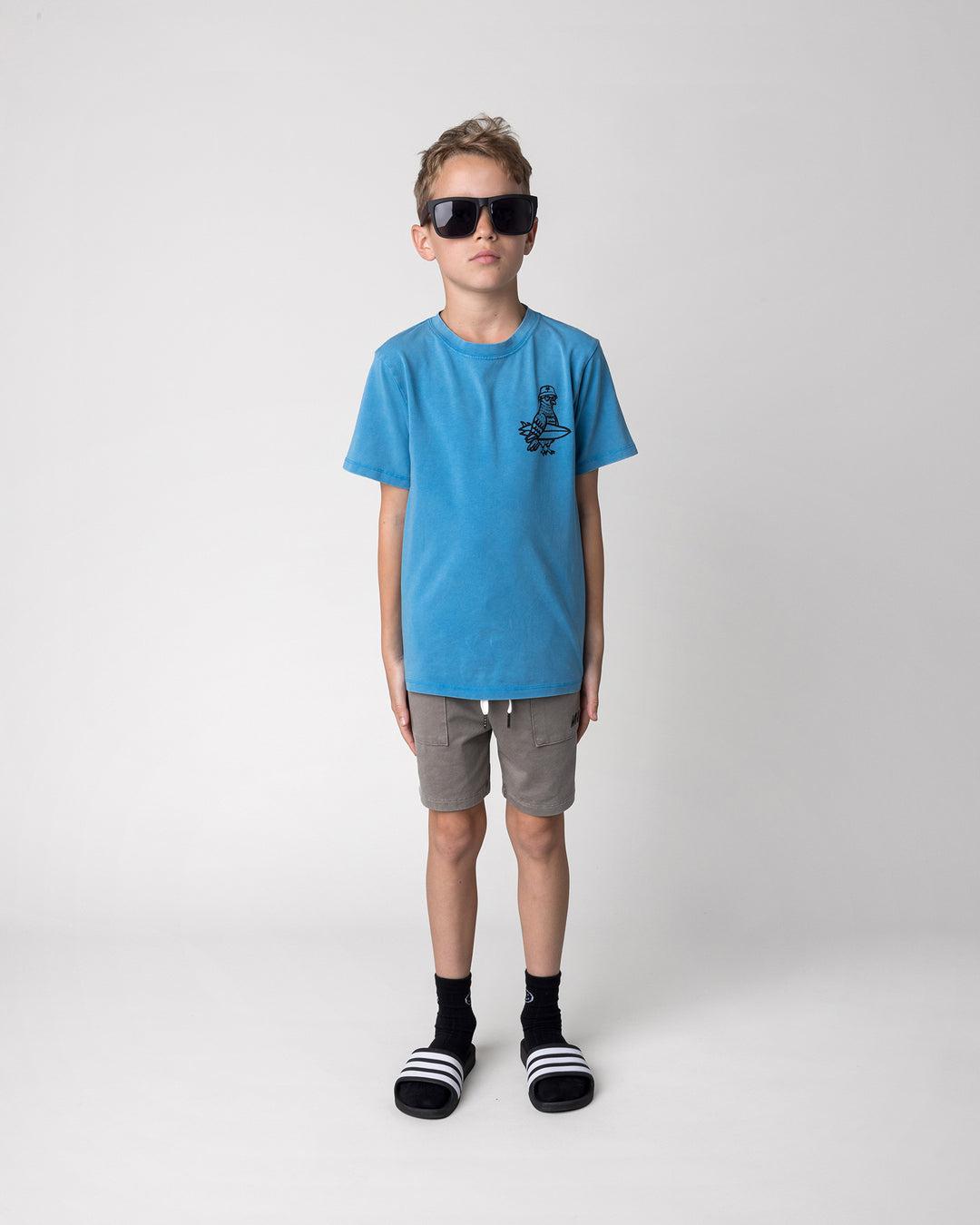 Kid wearing the Hi Pigeon Tee in sky wash with the Blasted Track Short in grey wash, front view