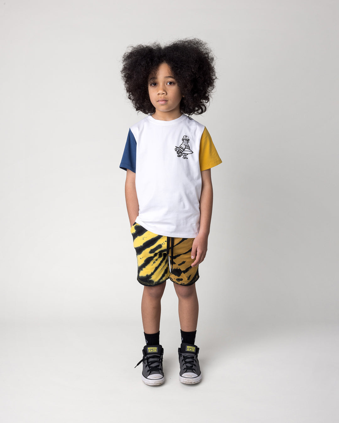 Kid wearing the Hi Pigeon Tee in white, midnight and yellow with the Duo Tie Dye Short in lemon and rust, front view