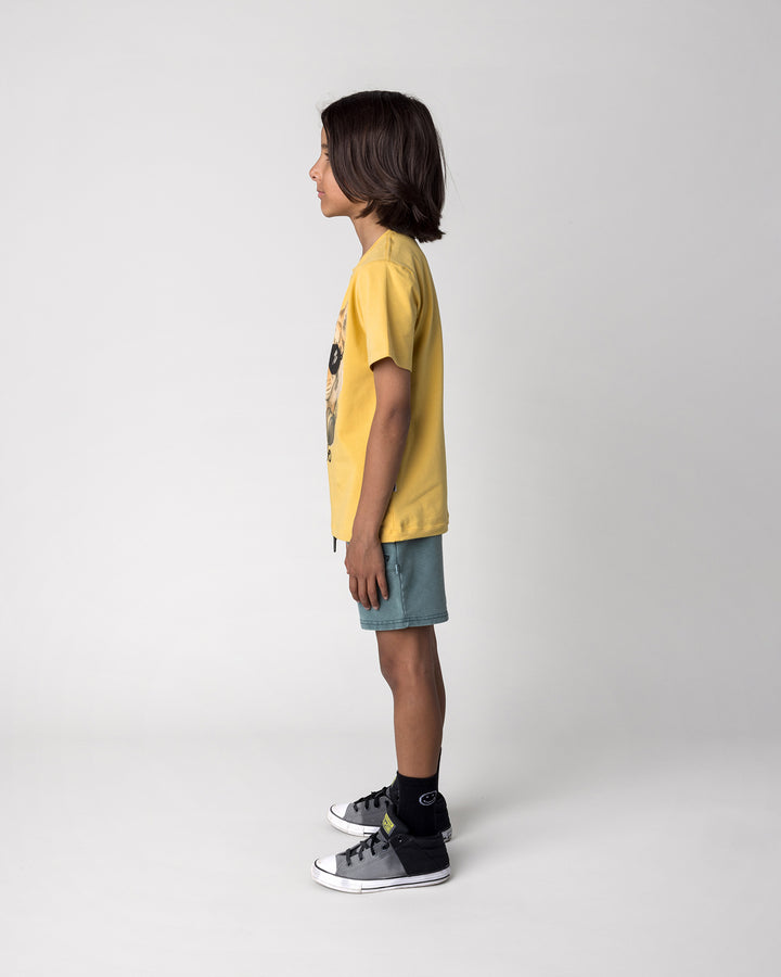 Kid wearing the Headphones Tiger Tee in dull yellow with the Blasted Track Short in forest wash, side view
