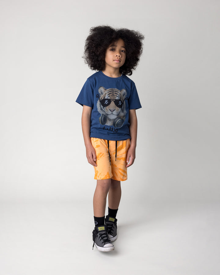 Kid wearing the Headphones Tiger Tee in midnight with the Splatter Short in orange, front view