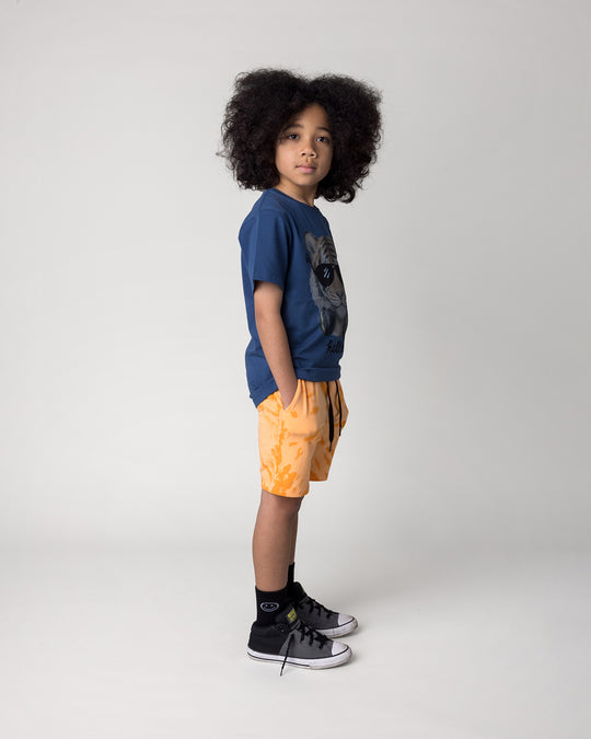Kid wearing the Headphones Tiger Tee in midnight with the Splatter Short in orange, side view