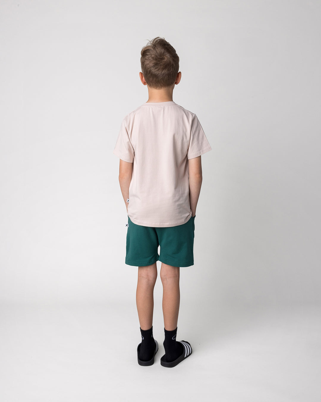 Kid wearing the Headphones Tiger Tee in stone with the Rib Pocket Short in kelly green, back view