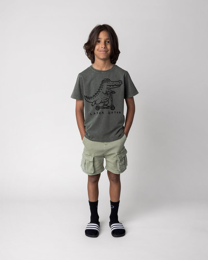 Kid wearing the Later Gator Tee in olive wash, front view