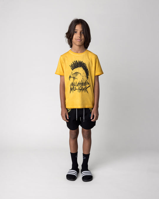 Kid wearing the Mo-Hawk Tee in mustard wash with the Badges Short in black, front view