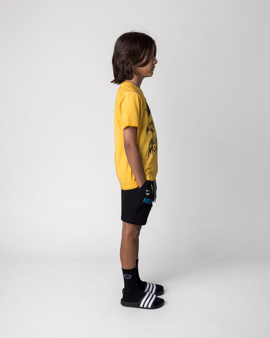 Kid wearing the Mo-Hawk Tee in mustard wash with the Badges Short in black, side view