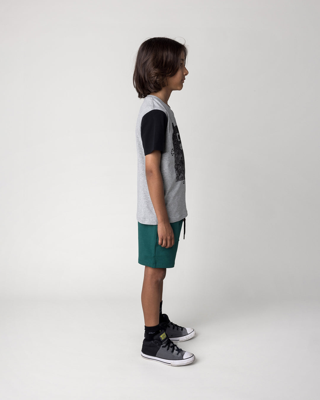 Kid wearing the Patchwork Monster Tee in grey marle and black with the Track Short in kelly green, side view