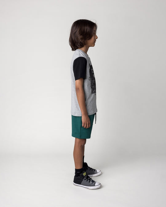 Kid wearing the Patchwork Monster Tee in grey marle and black with the Track Short in kelly green, side view