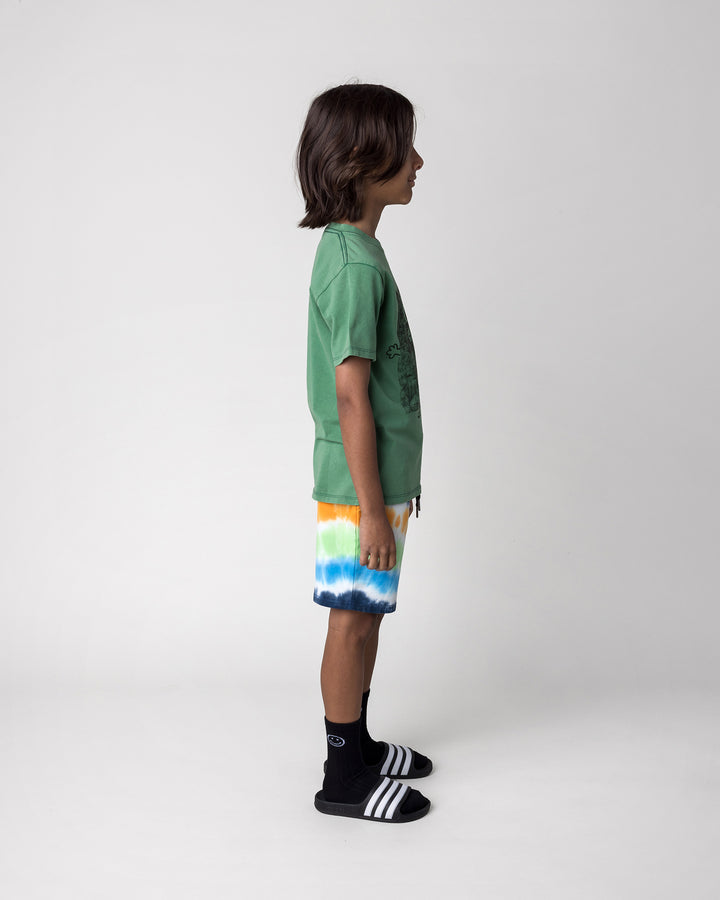 Kid wearing the Patchwork Monster Tee in turf wash with the Airwaves Short in navy, side view