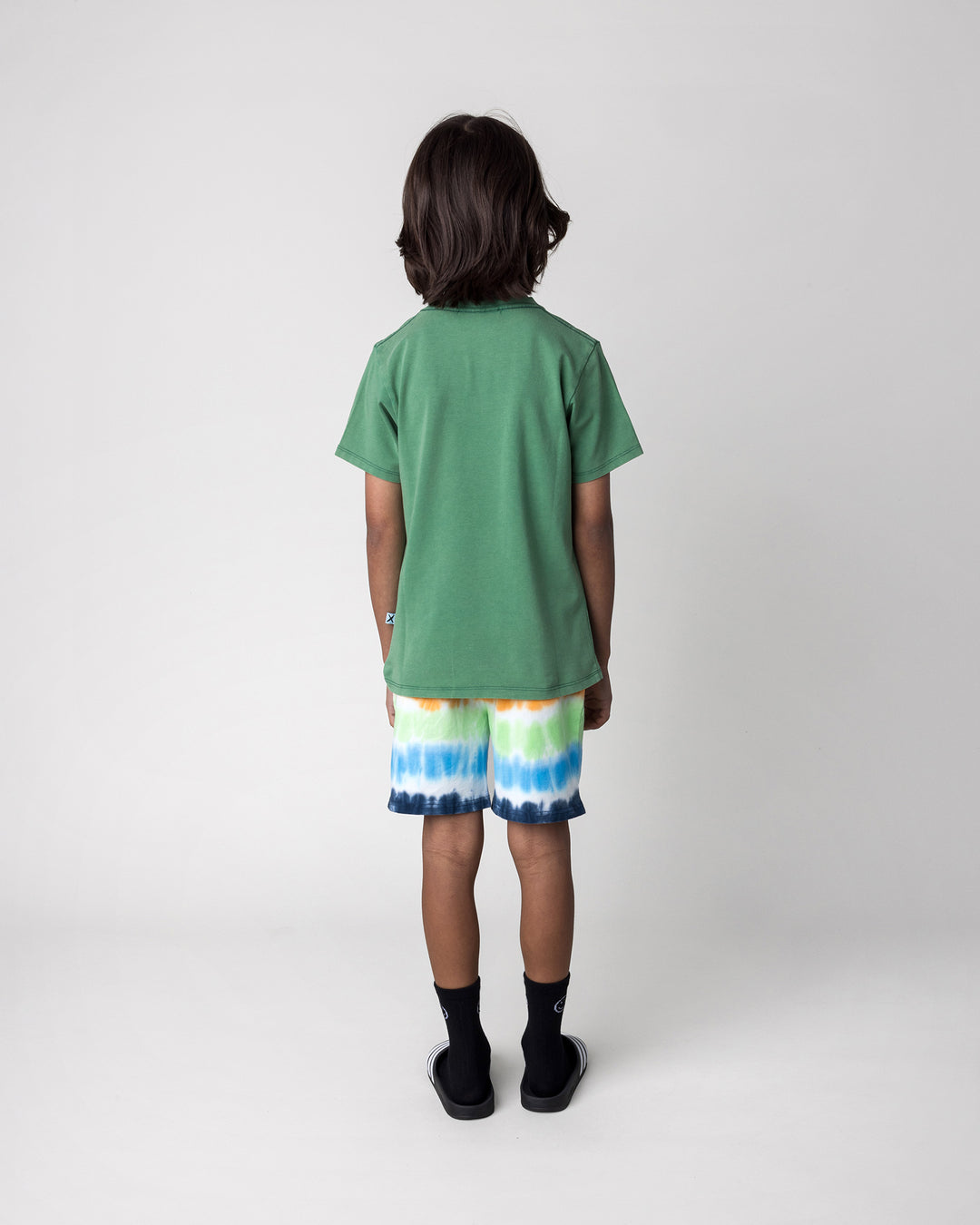 Kid wearing the Patchwork Monster Tee in turf wash with the Airwaves Short in navy, back view
