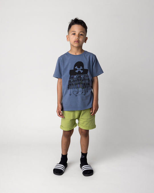 Kid wearing the Pirate Skater Tee in blue wash with the Roller Short in lime, front view