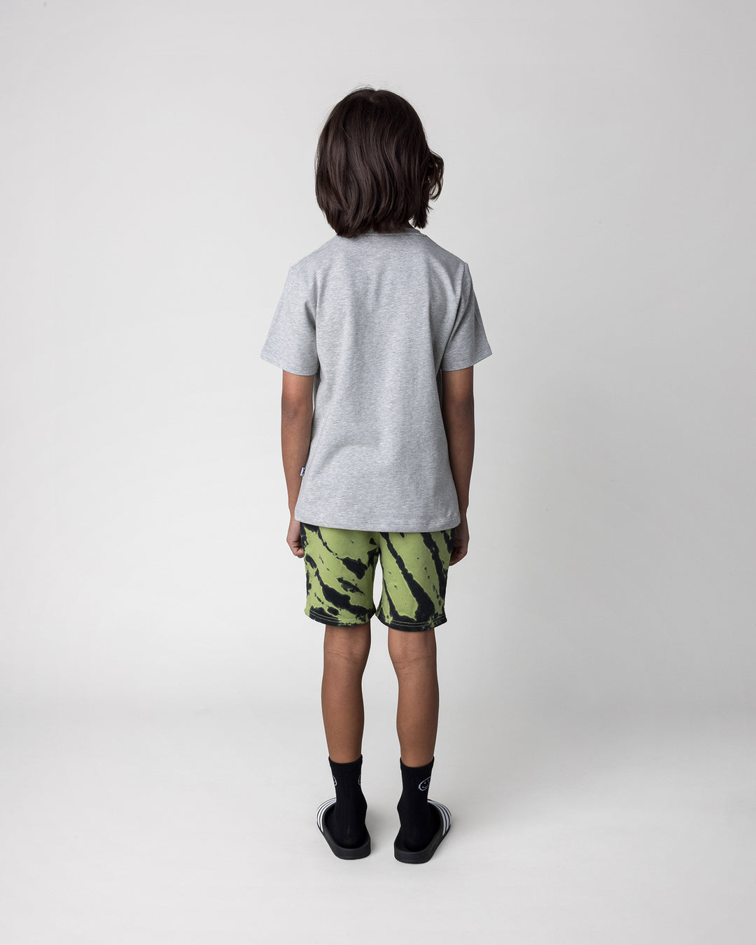 Kid wearing the Pirate Skater Tee in grey marle with the Strike Short in lime, back view