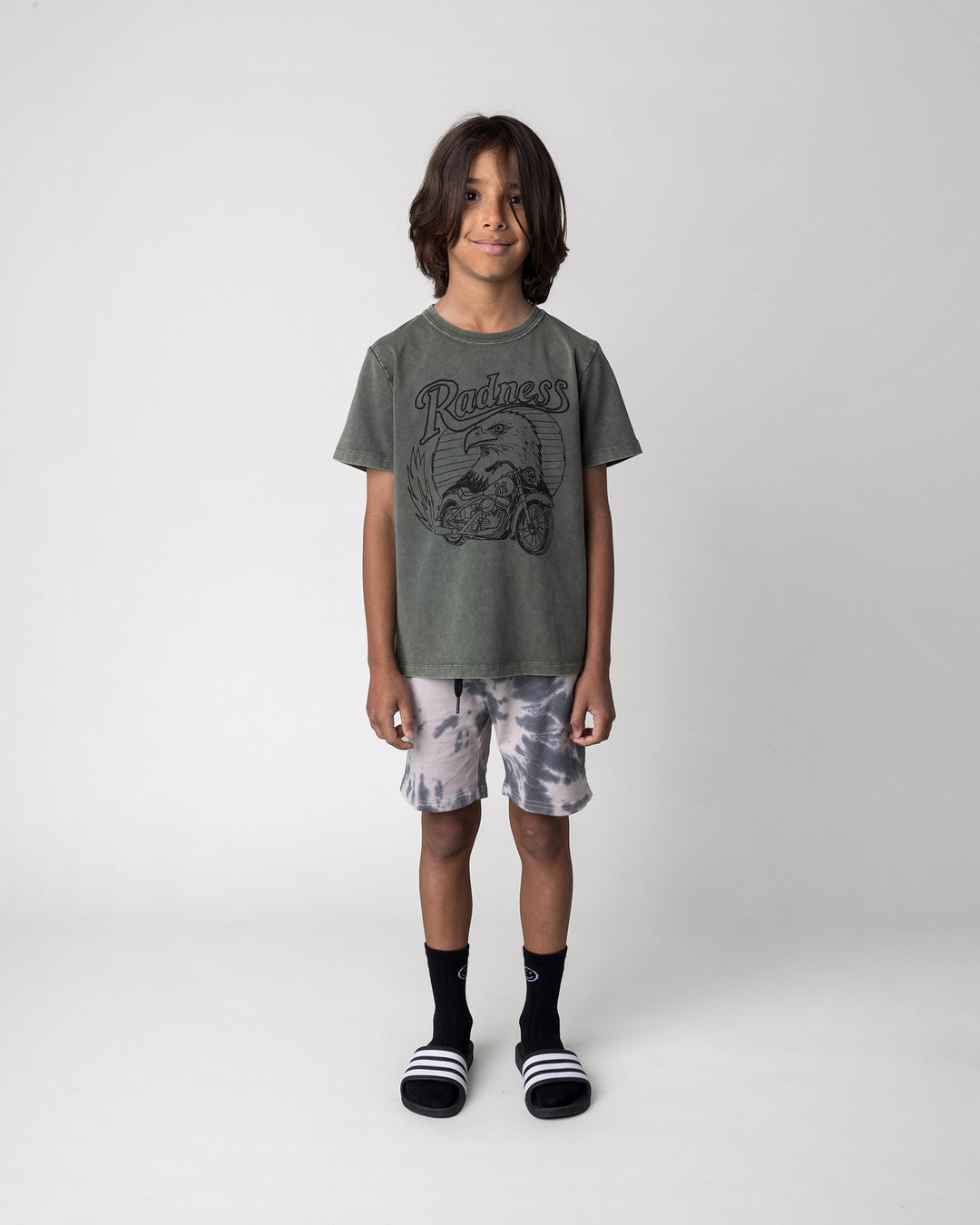 Kid wearing the Radness Tee in olive wash with the Splatter Short in grey, front view