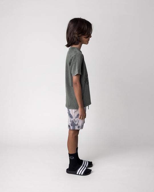 Kid wearing the Radness Tee in olive wash with the Splatter Short in grey, side view
