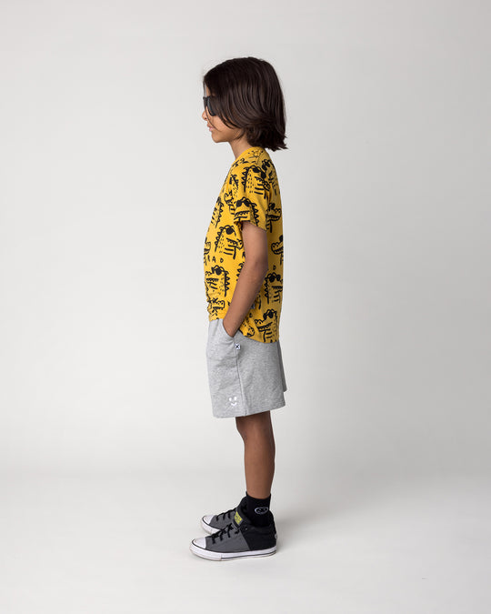 Kid wearing the Rad Croc Tee in mustard with the Smile Short in grey marle, side view
