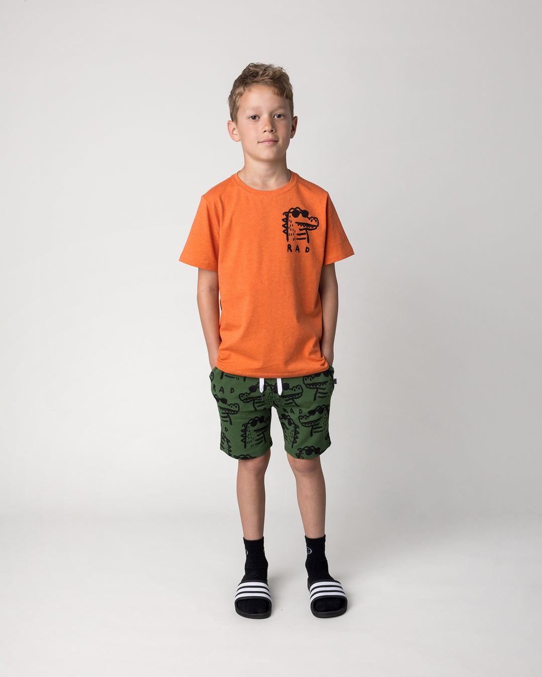 Kid wearing the Rad Croc Tee in orange marle with the Rad Croc Short in green, front view