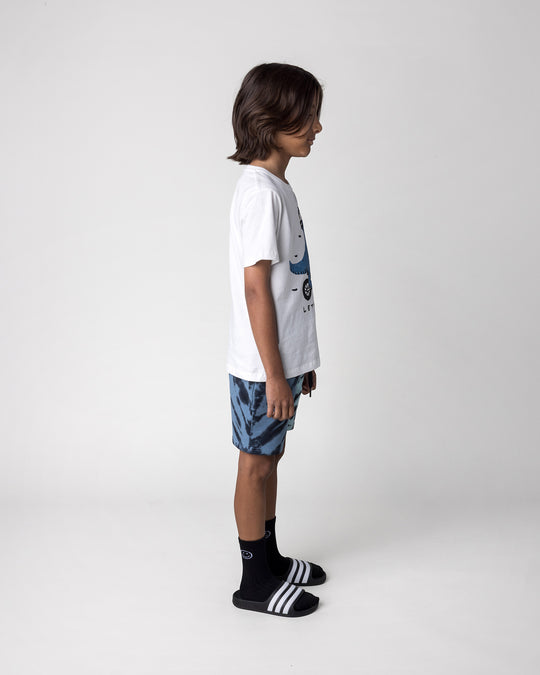 Kid wearing the Rex Rider Tee in off white with the Duo Tie Dye Short in blue and aqua, side view