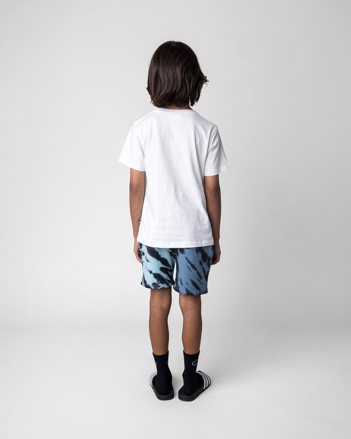 Kid wearing the Rex Rider Tee in off white with the Duo Tie Dye Short in blue and aqua, back view