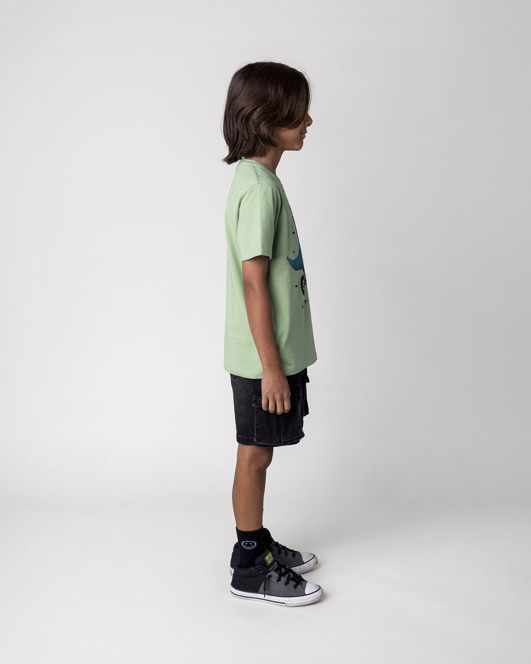 Kid wearing the Rex Rider Tee in sage, side view