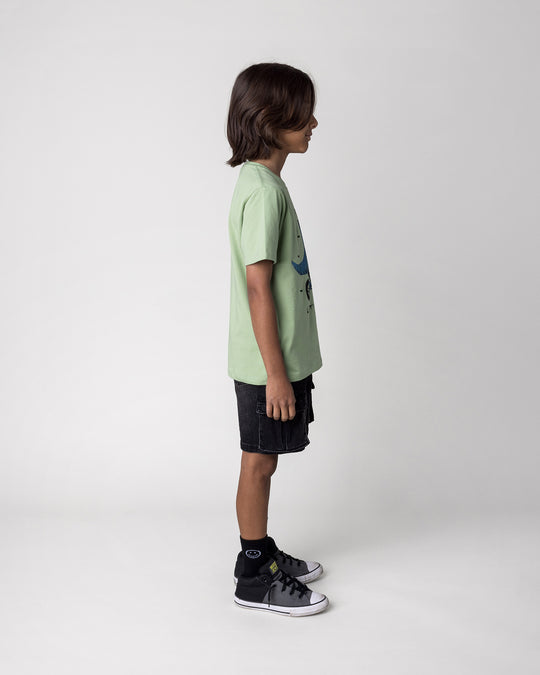 Kid wearing the Rex Rider Tee in sage, side view